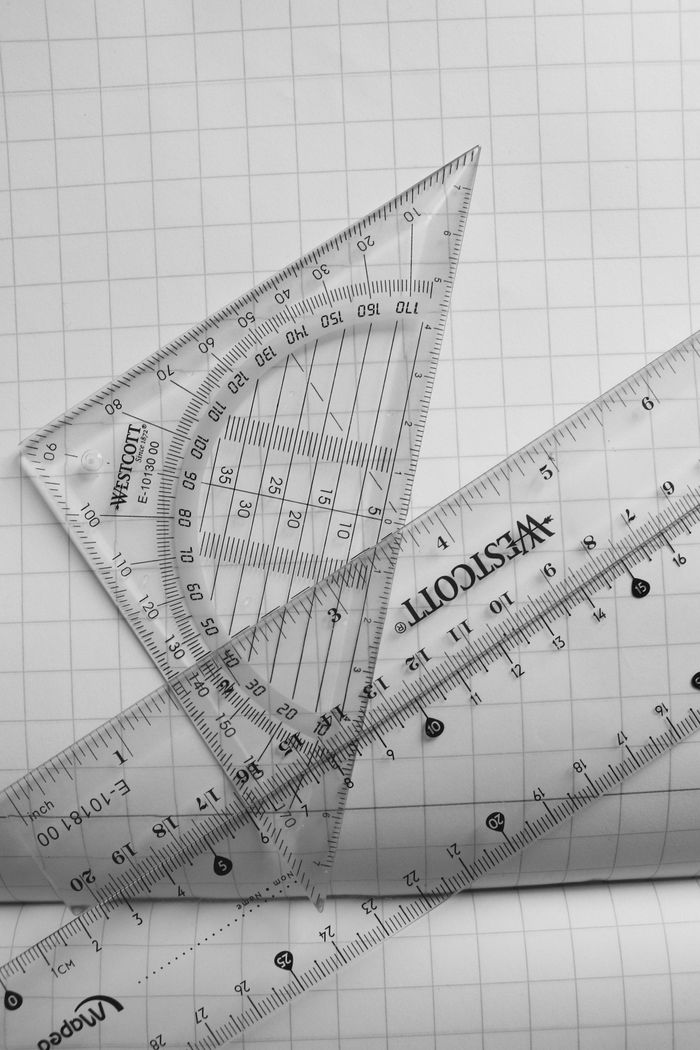 service-02 Clear plastic rulers and a protractor on graph paper, ideal for math and school subjects.